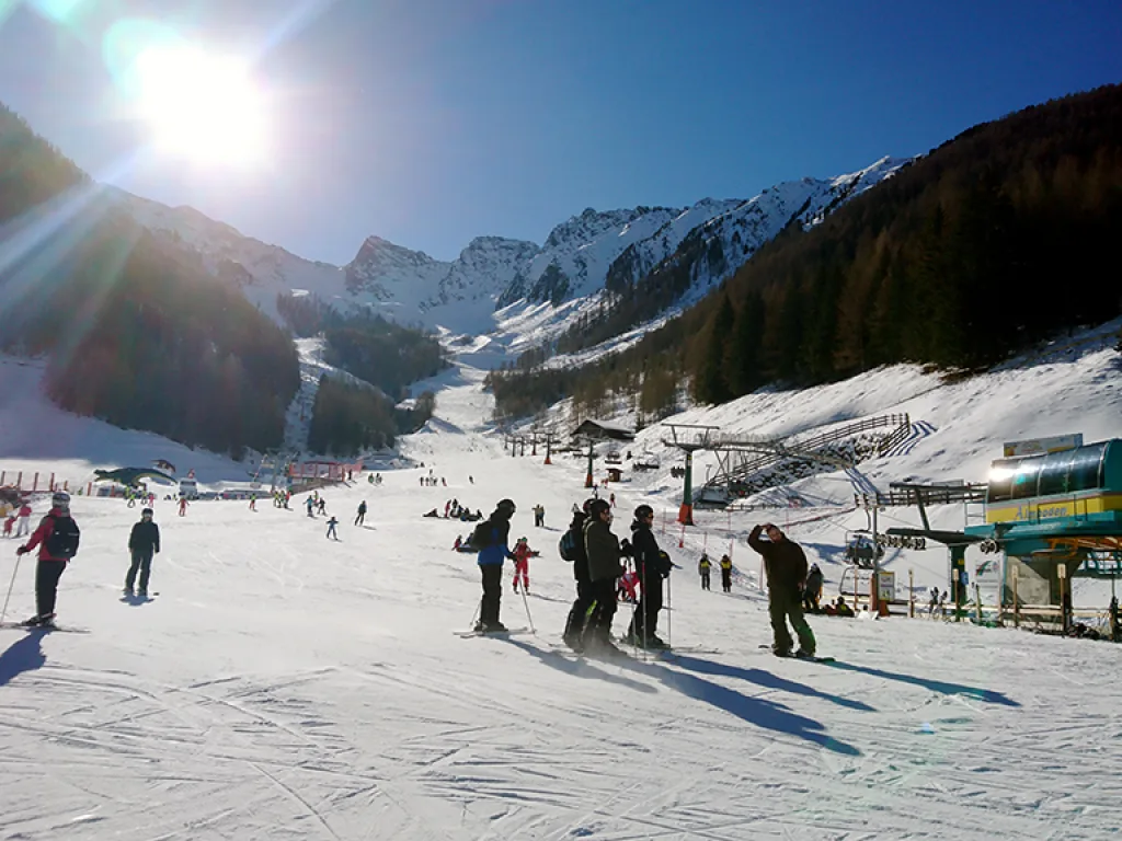 Blick gegen die Sonne über die Piste auf die Berge.